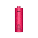 A tall, cylindrical pink bottle of Amika's 'The Protector' color-preserving hair conditioner, featuring a subtle floral pattern and black text, set against a plain white background.