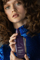 Person holding a purple bottle of Kevin Murphy product with a blue sequin top  - Hair Care Canada