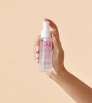Hand holding a bottle of 'Eleven' hair serum against a beige background - Hair Care Canada