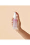 Hand holding a bottle of 'Eleven' hair serum against a beige background - Hair Care Canada