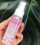 Hand holding a bottle of 'Smooth & Shine Anti-Frizz Serum' by Eleven Australia against a leafy background Hair Care Canada