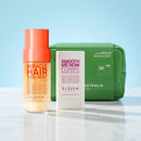 Hair care products including a bottle, balm, and pouch on a reflective surface with a light blue background.