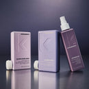 Three Kevin Murphy haircare products in a row on a dark reflective surface: a pale lavender box of Blonde Angel Wash, a matching box of Blonde Angel, and a darker mauve bottle of Untangled with a white spray top.