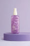 Purple hair care product bottle with white cap on a purple platform against a light purple background - Hair Care Canada