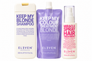 Three ELEVEN Australia haircare products from the Keep My Blonde line: a white shampoo bottle with a gold cap, a purple treatment pouch, and a white spray bottle with pink text, shown on a plain white background.