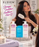 A woman with long dark hair holds a white ELEVEN Australia hair brush while standing in front of a mirror, with three ELVENEN Australia hair treatment bottles displayed on a tray below. The scene includes promotional text on the left and a bathroom-style background with flowers and framed wall art - Hair Care Canada