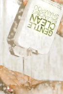 Hand pouring a clear liquid from a bottle labeled 'Gentle Clean' into another container - Hair Care Canada