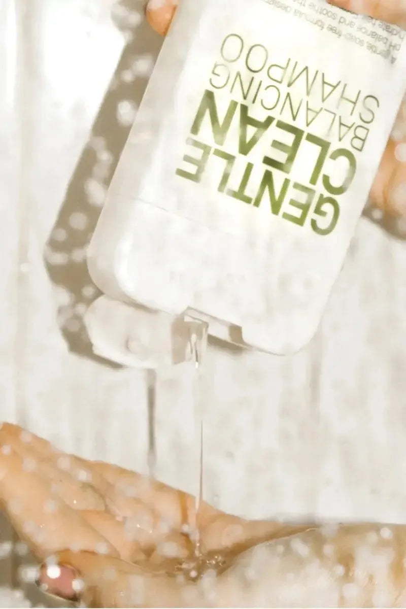 Hand pouring a clear liquid from a bottle labeled 'Gentle Clean' into another container - Hair Care Canada