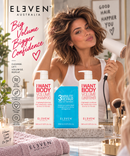 A woman in a bathroom setting holds a white hair dryer while three ELEVEN AUSTRALIA hair care products are displayed in the foreground: Volume Shampoo, 3 Minute Repair Volume Treatment, and Volume Conditioner. The scene includes promotional text, a towel, brushes, and a mirror - Hair Care Canada