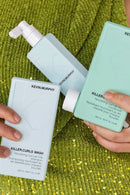 Kevin Murphy hair care products held by a person against a green textured background