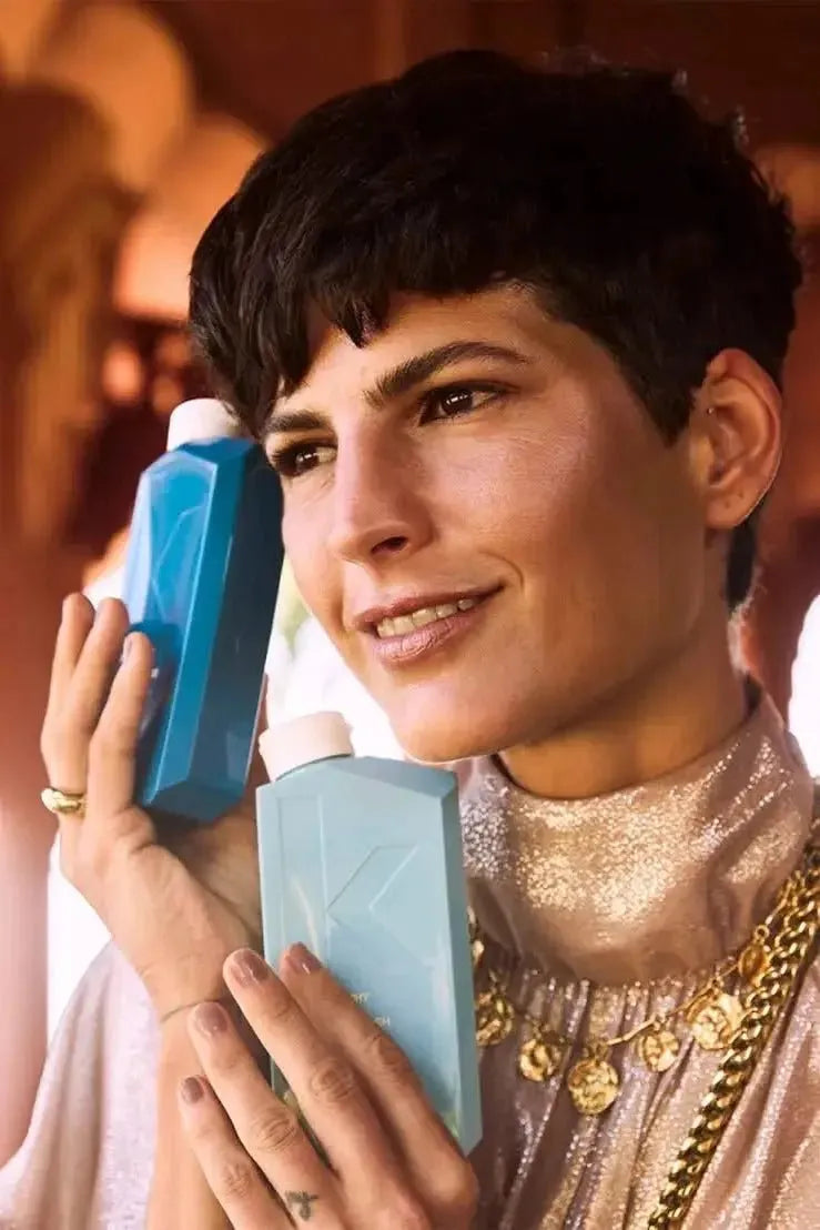 Woman holding two blue bottles with a blurred background - Hair Care Canada