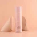 Kevin Murphy Doo-Over Dry Powder setting spray in a pale pink cylindrical bottle, styled on a peach background with two beige geometric props.