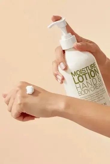 Hand applying lotion from a bottle labeled 'Moisture Lotion Hand & Body Cream' on a beige background - Hair Care Canada