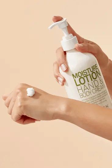 Hand applying lotion from a bottle labeled 'Moisture Lotion Hand & Body Cream' on a beige background - Hair Care Canada