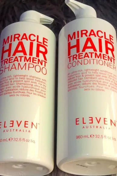 Two bottles of Eleven Australia Miracle Hair Treatment Shampoo and Conditioner on a textured surface Hair Care Canada